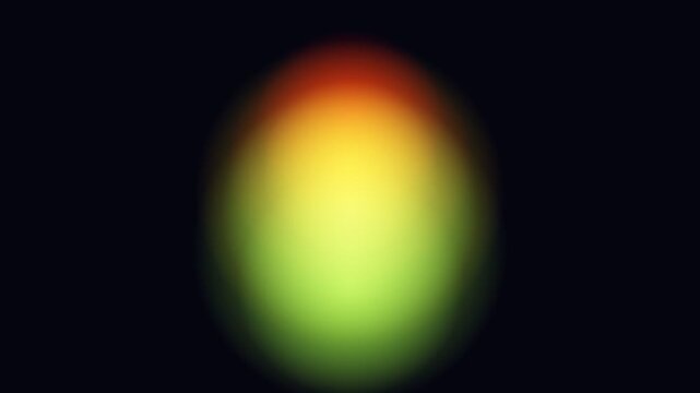 Blurred oval shape with a gradient of green, yellow, and red colors centered on a dark background.