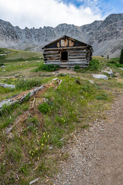 Ruins of former mining cabins on Mayflower Gulch Trail near Copper Mountain, Colorado under summer afternoon cloudscape.