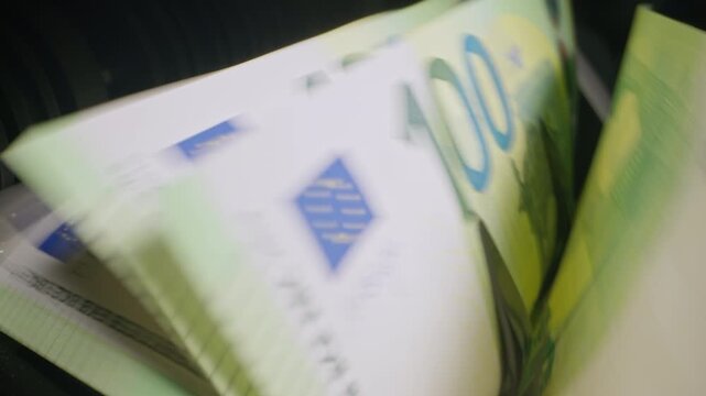 Euro banknotes passing through an automatic money counter before currency exchange. International finance, travel money and foreign exchange services