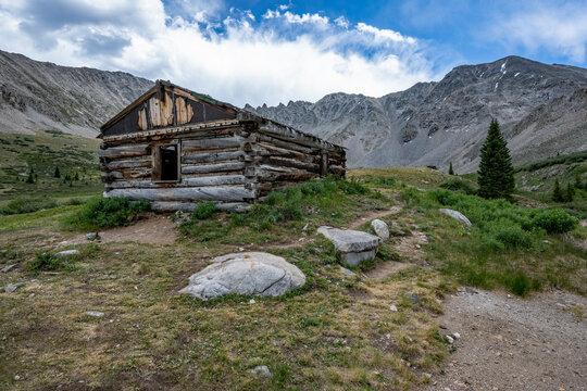 Ruins of former mining cabins on Mayflower Gulch Trail near Copper Mountain, Colorado under summer afternoon cloudscape.