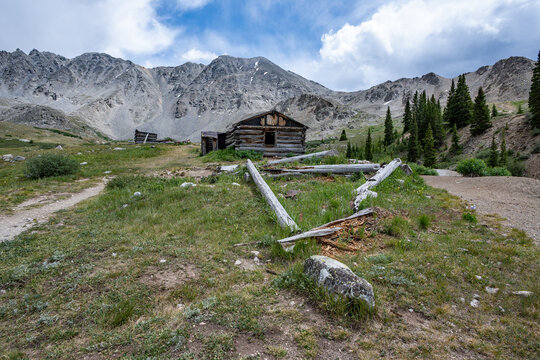 Ruins of former mining cabins on Mayflower Gulch Trail near Copper Mountain, Colorado under summer afternoon cloudscape.