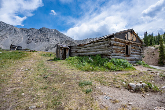 Ruins of former mining cabins on Mayflower Gulch Trail near Copper Mountain, Colorado under summer afternoon cloudscape.