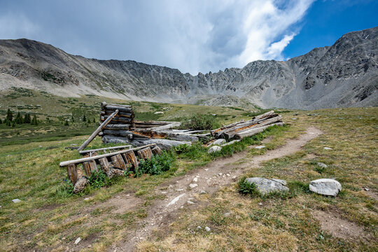 Ruins of former mining cabins on Mayflower Gulch Trail near Copper Mountain, Colorado under summer afternoon cloudscape.