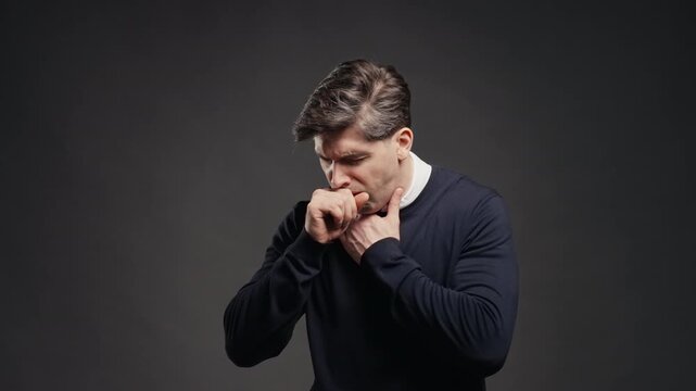 Young adult man Has Sore. Sick Guy Coughs With Swollen Throat On Grey Studio. Pain, ache. Seasonal flu, cold disease