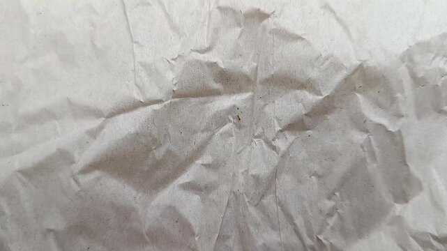 Close-up slow camera movement over crumpled white paper texture, abstract background for design.