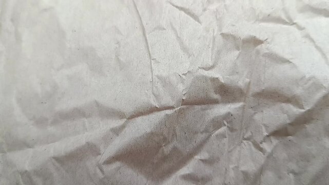 Close-up slow camera movement over crumpled white paper texture, abstract background for design.
