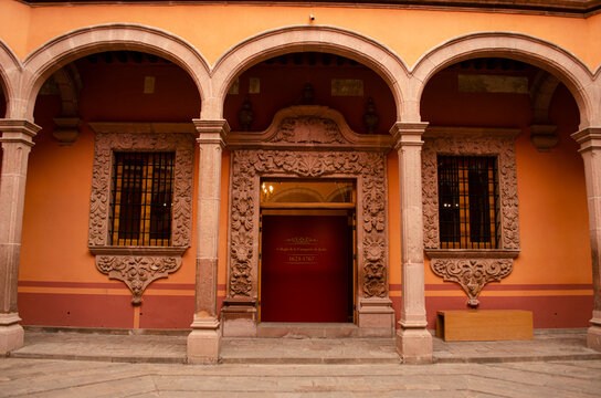 Archway and carved pink quarry stone doorway at the historic Antigua Casa de Moneda in San Luis Potosi, Mexico. Colonial Baroque architecture with ornate windows and central courtyard gallery.