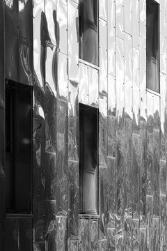 Metallic reflection bends across vertical panels in a close study of architecture, while the abstract facade turns urban texture into distortion across the building surface.