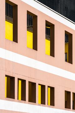 Pink windows catch strong shadows in a close study of architecture, while the urban facade turns measured geometry into pattern across the building exterior.
