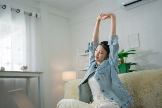 Work break and relaxation concept with a young woman stretching her arms beside a laptop at home, enjoying rest after work, relaxation, stretching, wellness, break, lifestyle