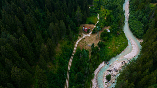 aerial view of a village with river and buildings in neutral calm setting from above with concrete, wood, and metal materials and green, brown, blue, and red colors.
