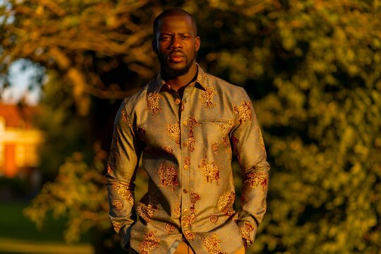Golden light bathes a man in a patterned shirt