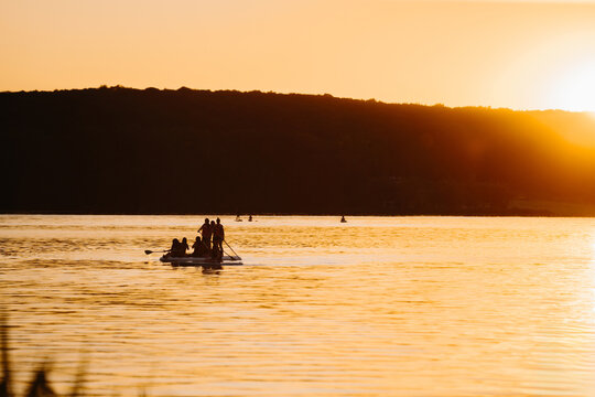 Group stand up paddleboarding at golden sunset