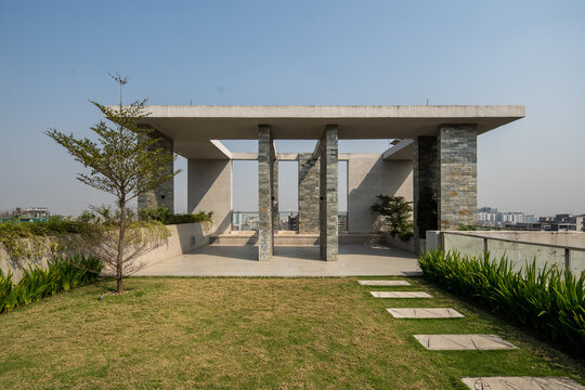 Modern Rooftop Garden with Open Pavilion, Stone Columns, Green Lawn, and Stepping Stone Pathway