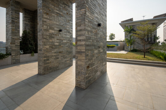 Modern Outdoor Courtyard with Stone Columns, Paved Terrace, Landscaped Garden, and Contemporary Architecture
