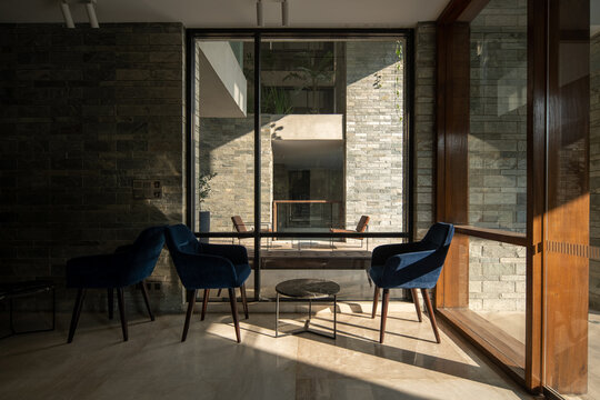 Modern Interior Sitting Area with Blue Lounge Chairs, Glass Windows, Stone Walls, and Warm Natural Light