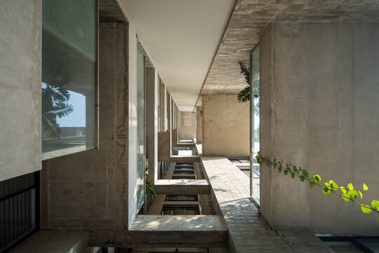 Modern Residential Courtyard with Long Corridor, Stone Walls, Large Windows, and Natural Light