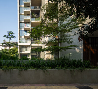 Aalo LensModern Residential Building with Glass Balconies, Stone Walls, Green Landscaping, and Mature Trees