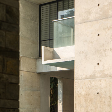 Modern Concrete Building Exterior with Glass Balcony, Large Windows, and Minimalist Architectural Design