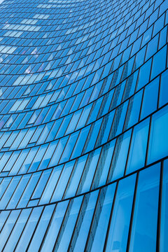 Rows sweep upward on an urban building, following the curved facade as repetition takes shape in blue across glass before windows organize architecture into precise geometry.