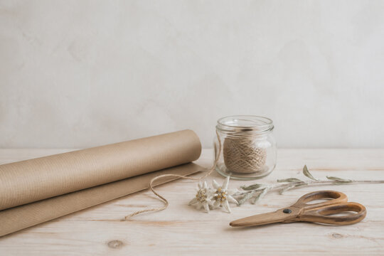 Minimal gift wrapping station with kraft paper, twine, dried edelweiss and scissors, alpine simplicity concept