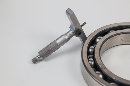 Micrometer depth gauge and steel ball bearing isolated on white background with copy space.