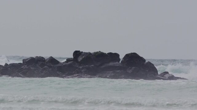 Telephoto shot of Slow motion waves hitting rocks in tortuga bay beach Galapagos