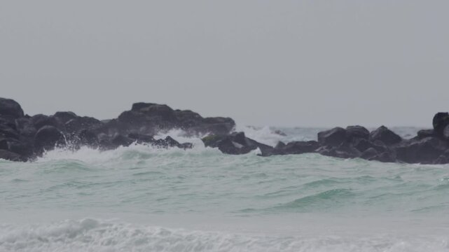 Telephoto shot of Slow motion waves hitting rocks in tortuga bay beach Galapagos