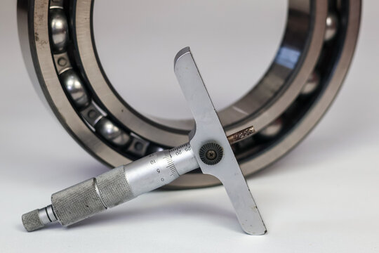 Measuring steel ball bearing with a micrometer depth gauge isolate on white.