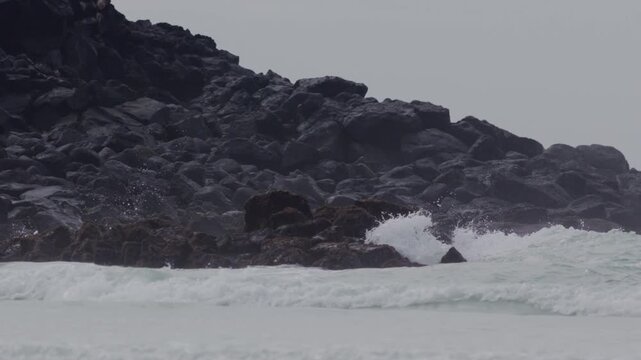 Telephoto shot of Slow motion waves hitting rocks in tortuga bay beach Galapagos