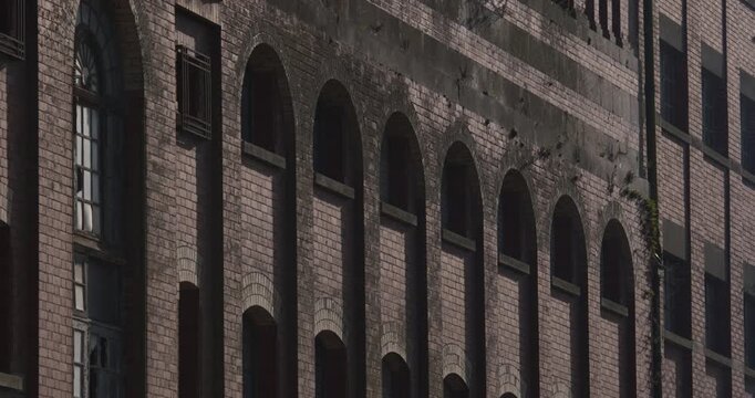 Old derelict industrial red brick building facade window arches