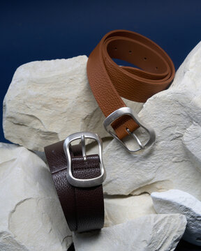 Brown and black leather belts on display with rocks