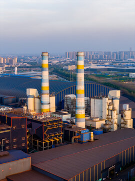  Industrial chimneys of a power plant at dusk over urban skyline