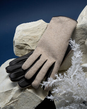 Winter gloves placed on white rocks with blue background