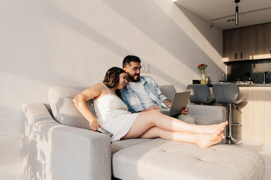 Relaxed young couple looking at a laptop together on a sofa