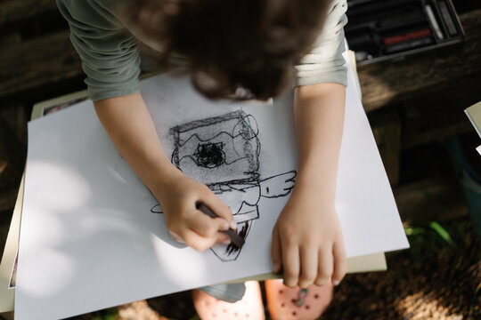 Inspired curly haired boy creating outdoor artwork