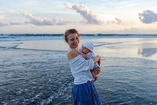 Mother Holding Baby on Beach at Sunset