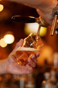 Fresh draught beer is being poured into a clear glass.