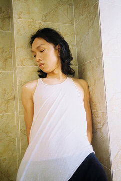 Young Person Leaning Against Tiled Wall, Looking Down