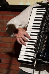 A musician playing the piano keys of a black accordion. © Ferran