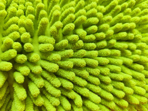 Close up macro view of a bright green microfiber chenille cleaning cloth with soft textured fibers, abstract household fabric background.