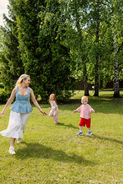 Children and mother play in a green park area.