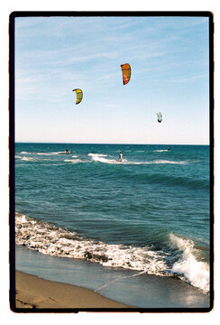 Kites pulling riders across rolling coastal swells