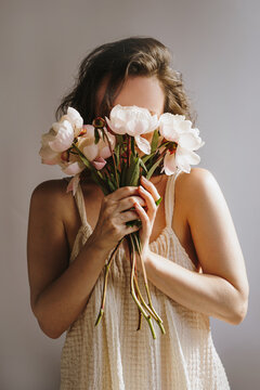 Elegant woman holding peony flowers.
