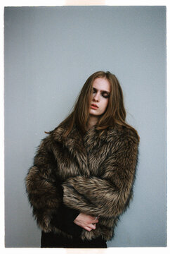 Model poses in fur coat against a light wall in a studio