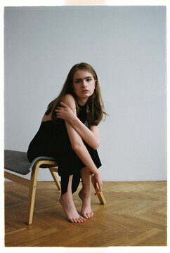 Woman sitting on a chair with bare feet and arms crossed
