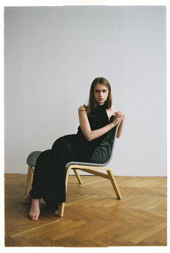 Model sits on modern chair in studio setting during daylight