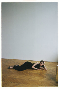 Woman lying on wooden floor in empty room