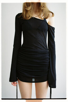 Model poses in black dress with asymmetrical design
