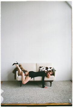 Model poses on a couch in a studio setting during a fashion shoot